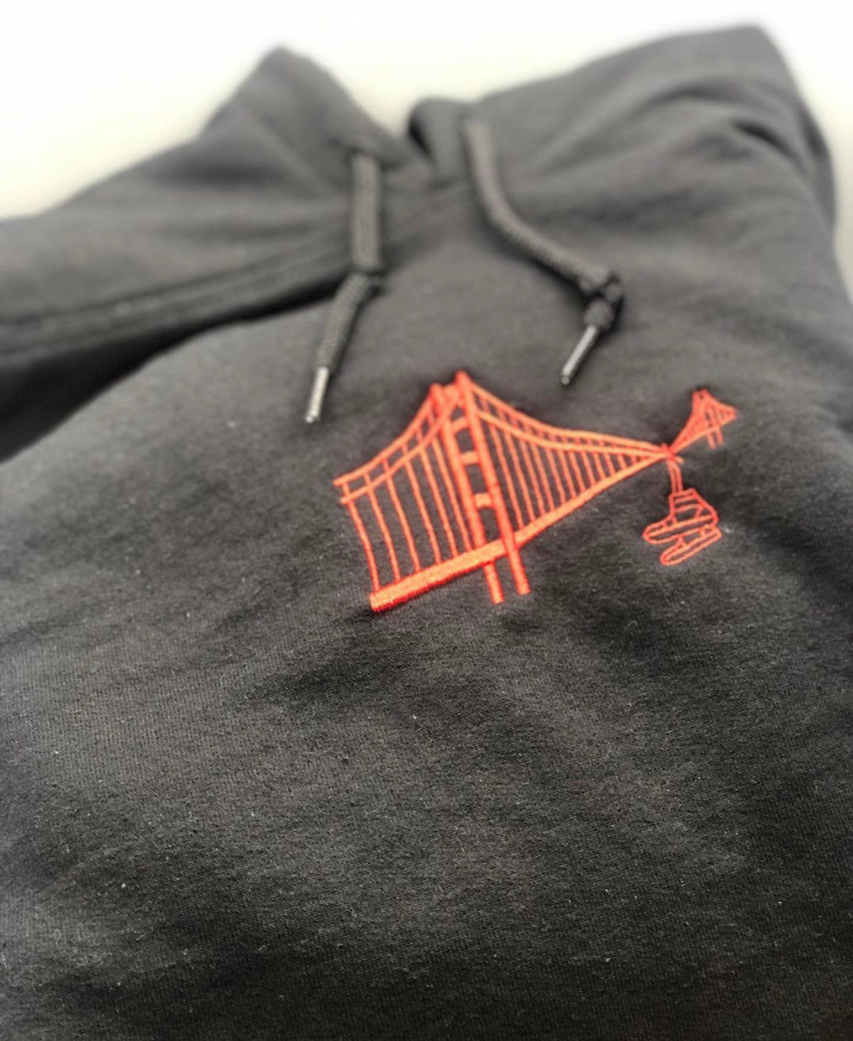 black hoodie with shoes or sneakers hanging from golden gate bridge